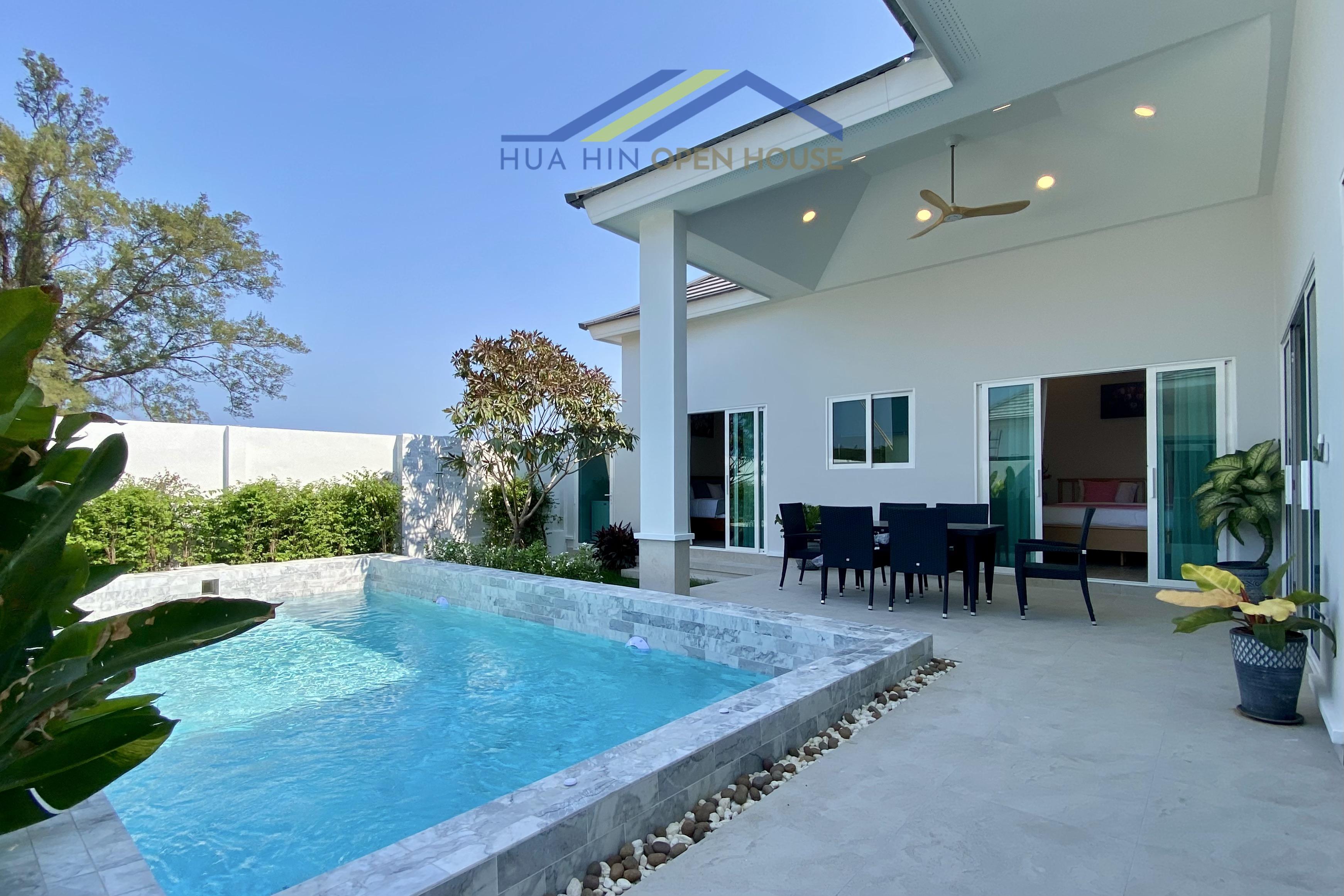 Modern 3-bedroom villa in Hua Hin featuring a private pool, outdoor dining area, and lush greenery. Sunny blue sky above.