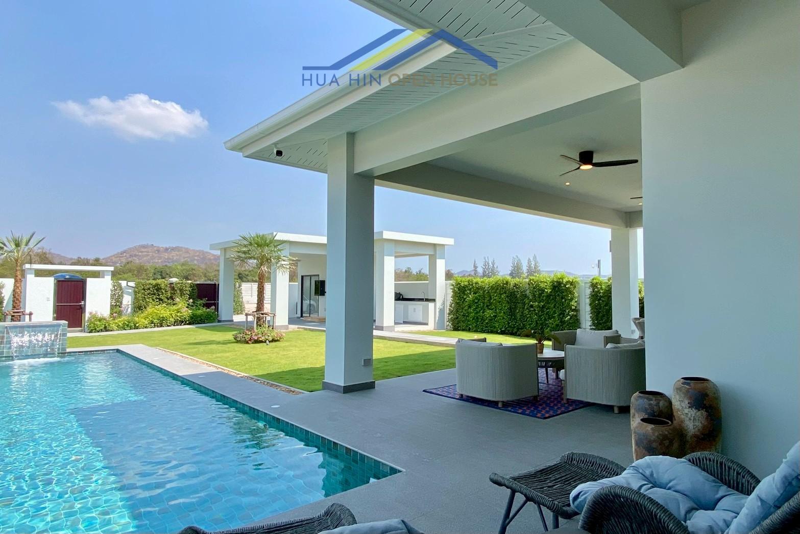 Modern pool villa with lush garden, outdoor seating, and mountain views in Hin Lek Fai, Hua Hin. Energy-efficient design.