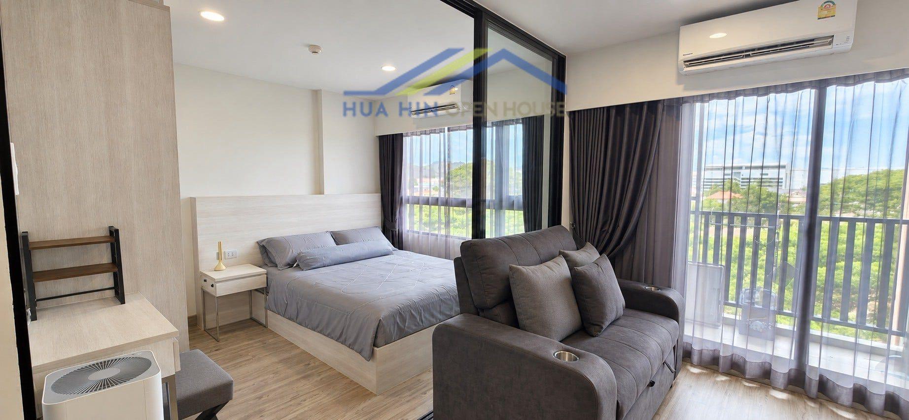 Modern condo interior featuring a cozy bedroom, stylish sofa, and large windows with natural light in dusitD2 Residences.