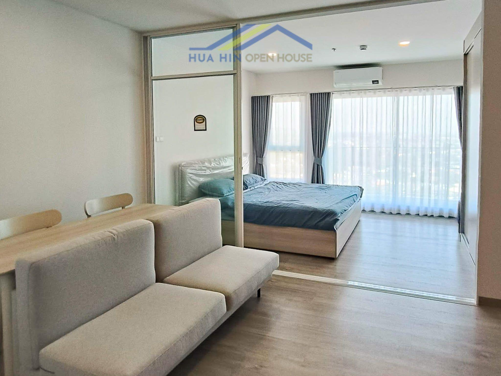 Bright condo interior featuring a cozy seating area and a bedroom with large windows offering scenic views.