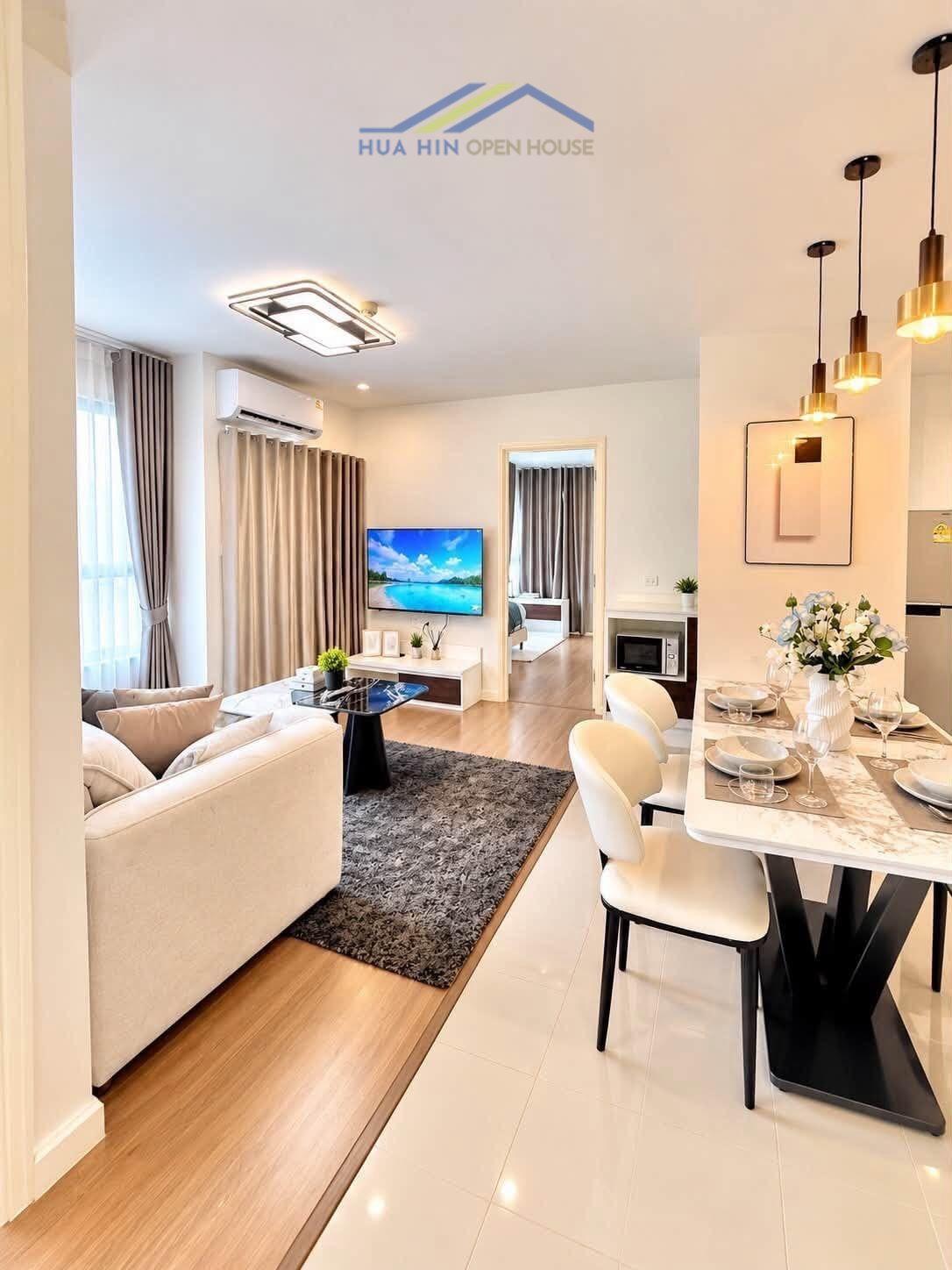 Stylish living area of a 2-bedroom condo featuring modern furnishings, dining table, and mountain views in Hua Hin.