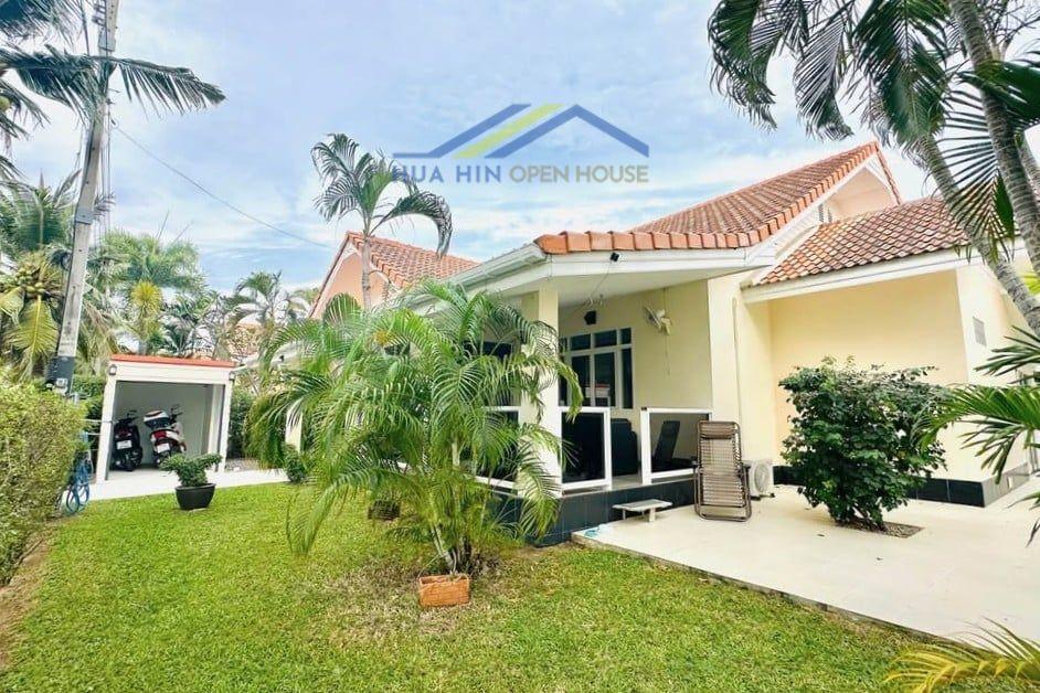 3-bedroom garden villa with lush greenery, patio seating, and nearby parking in North Hua Hin, close to Palm Hills Golf Cours