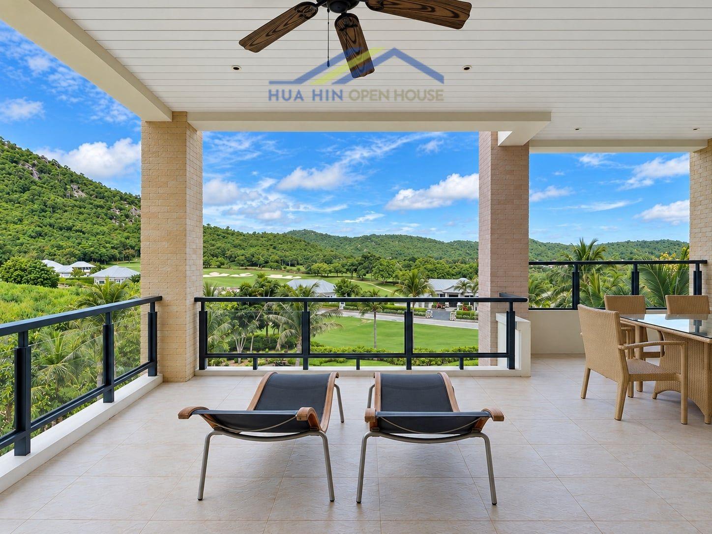 Spacious balcony with lounge chairs and dining area, offering stunning views of lush hills and greenery in Hua Hin.