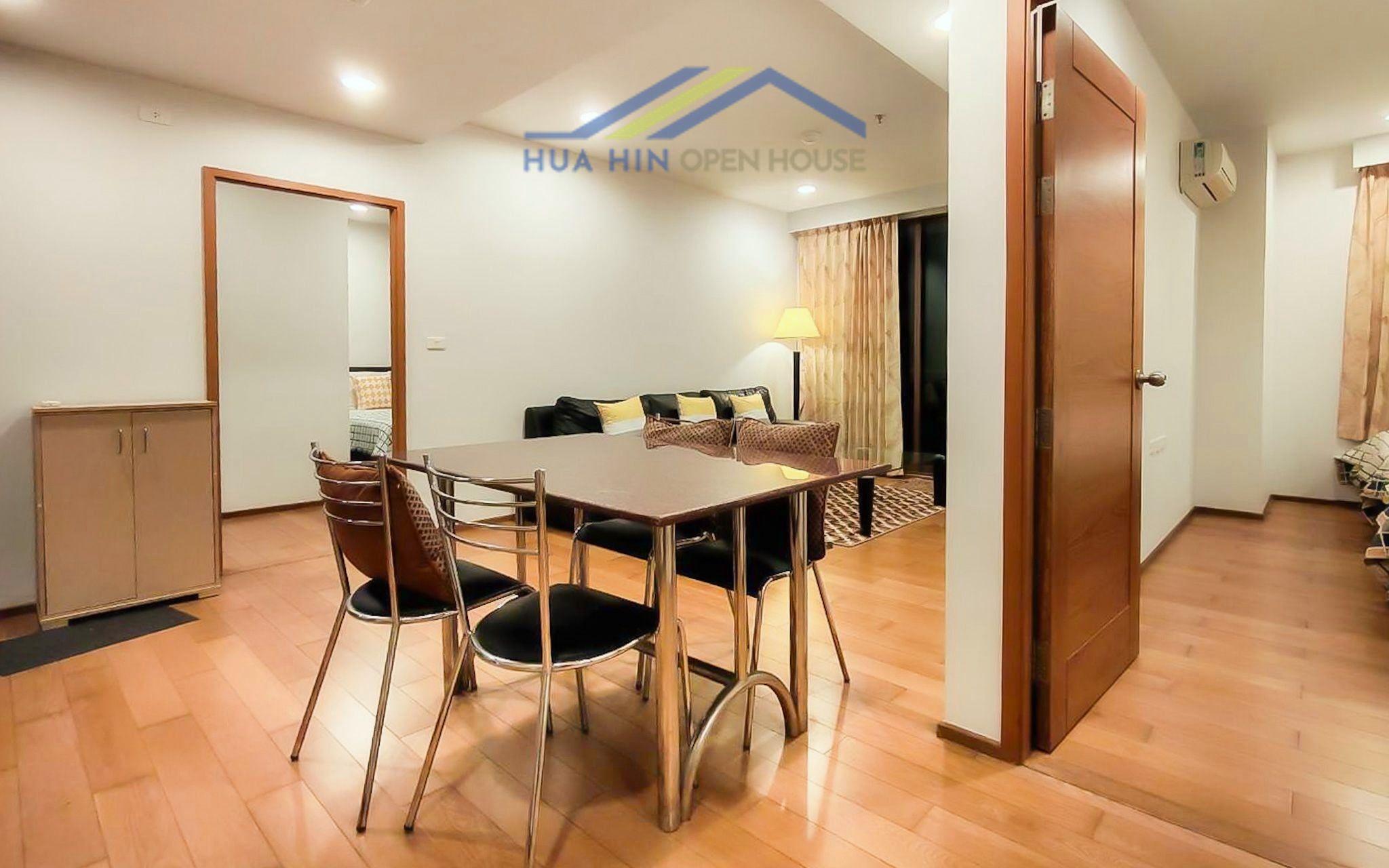 Modern living space featuring a dining table, sleek chairs, and a cozy sofa with decorative cushions in a beachfront condo.