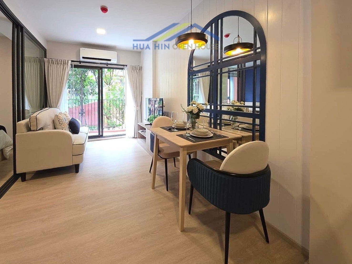 Stylish condo interior featuring a cozy living area, dining table, and balcony access with natural light.