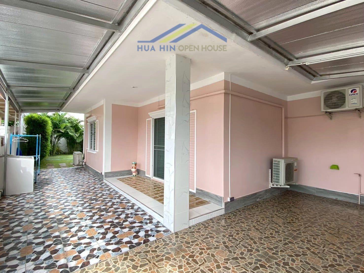 Spacious outdoor area with patterned tiles, pink walls, and greenery in a 4-bedroom garden home in Hua Hin.