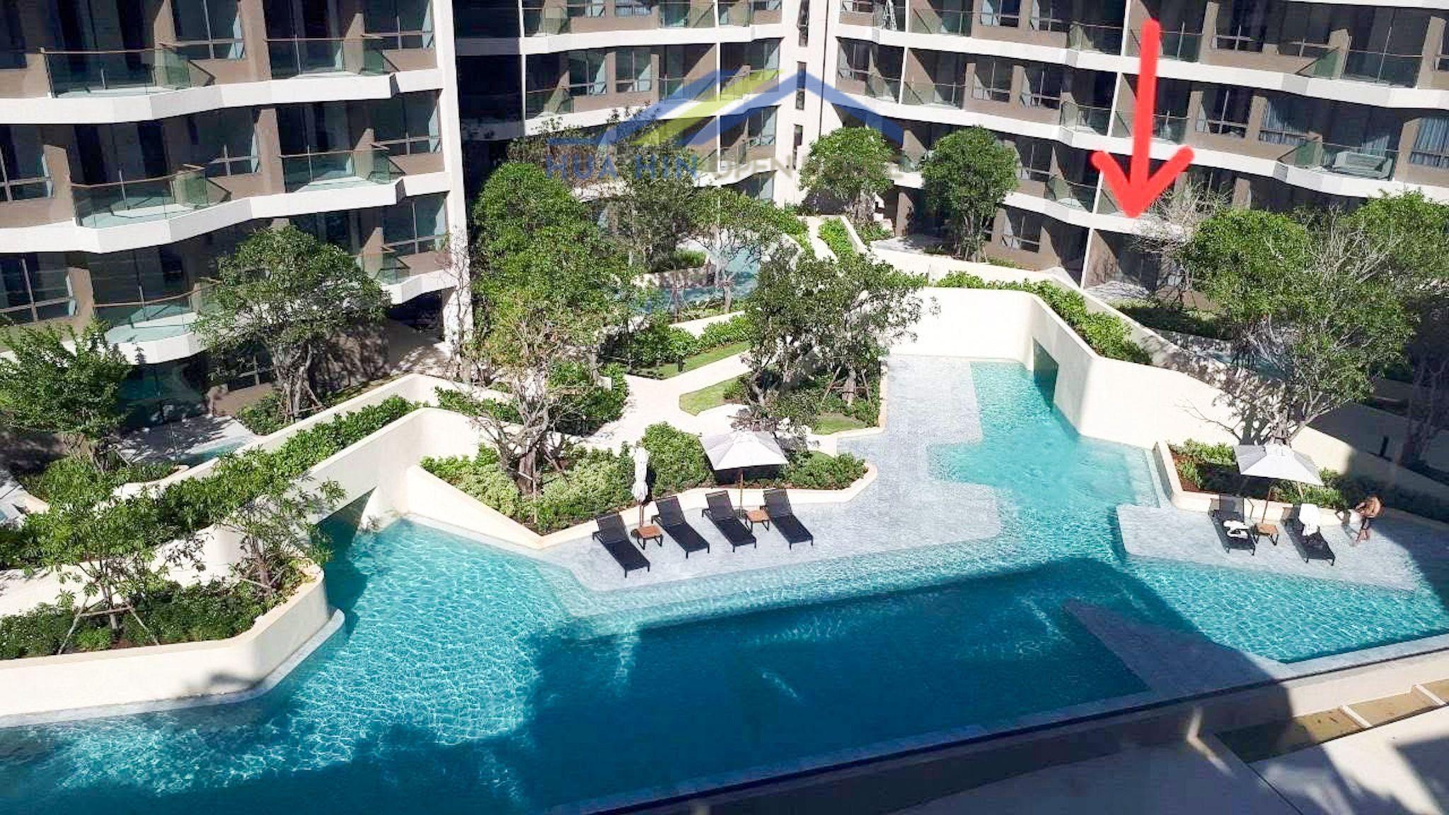 Spacious pool area with lush landscaping and sun loungers at Veranda Residence Hua Hin. Ideal for relaxation and leisure.