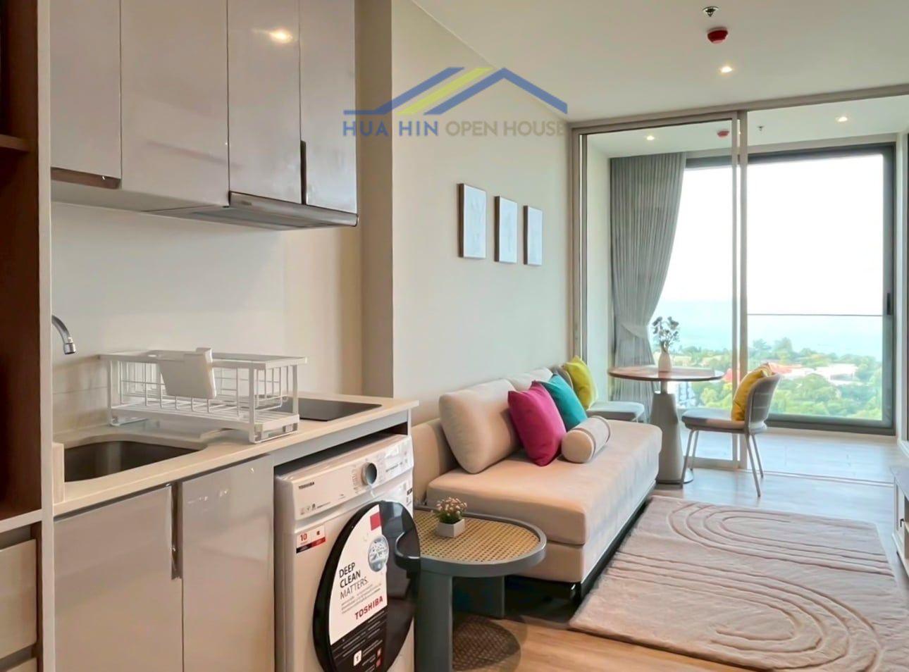 Modern 1-bedroom condo interior with sea view, featuring a cozy living area, kitchenette, and dining space.