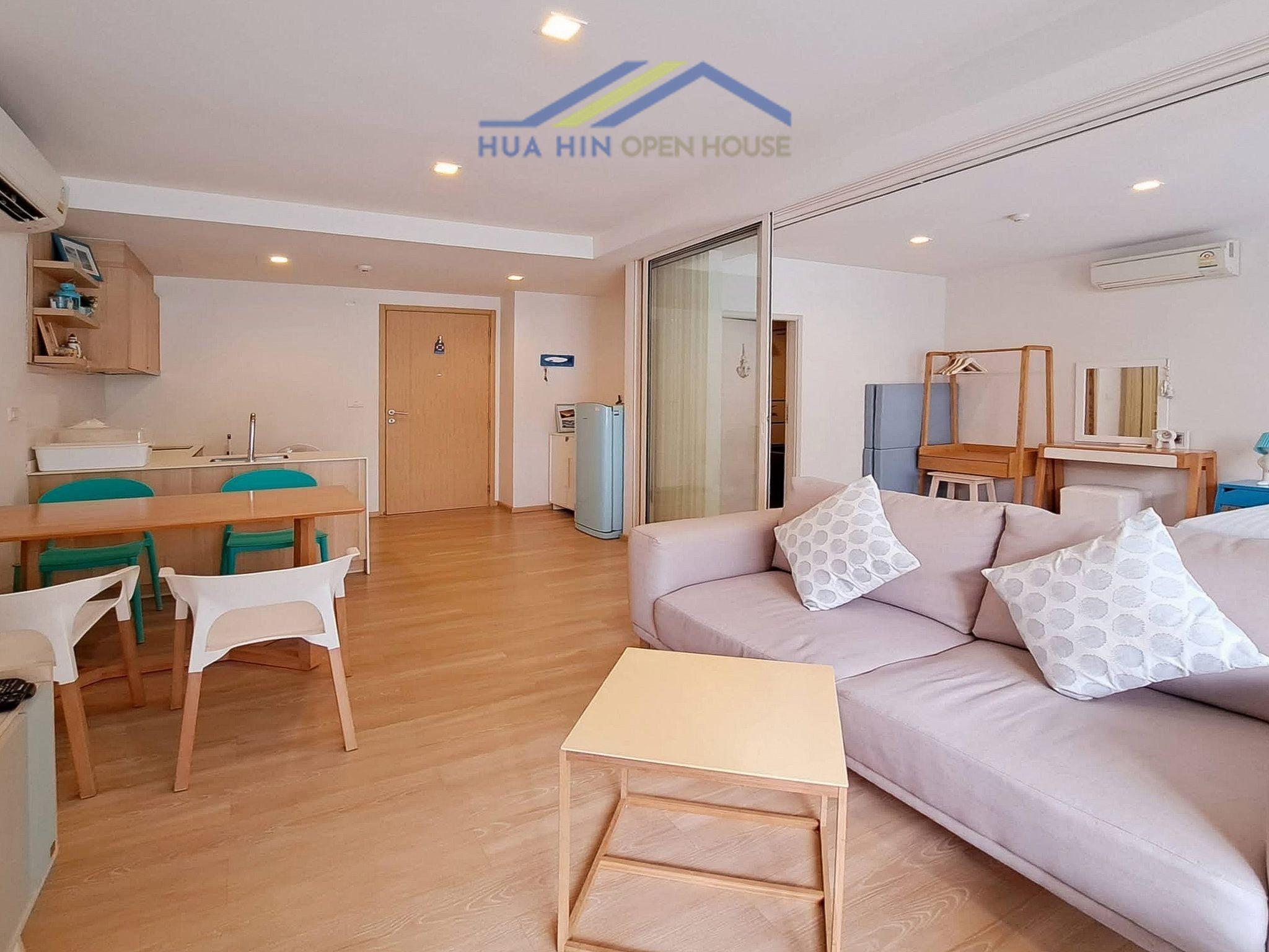 Spacious 1-bedroom condo interior featuring a living area, dining table, and modern kitchen appliances. Bright and inviting.