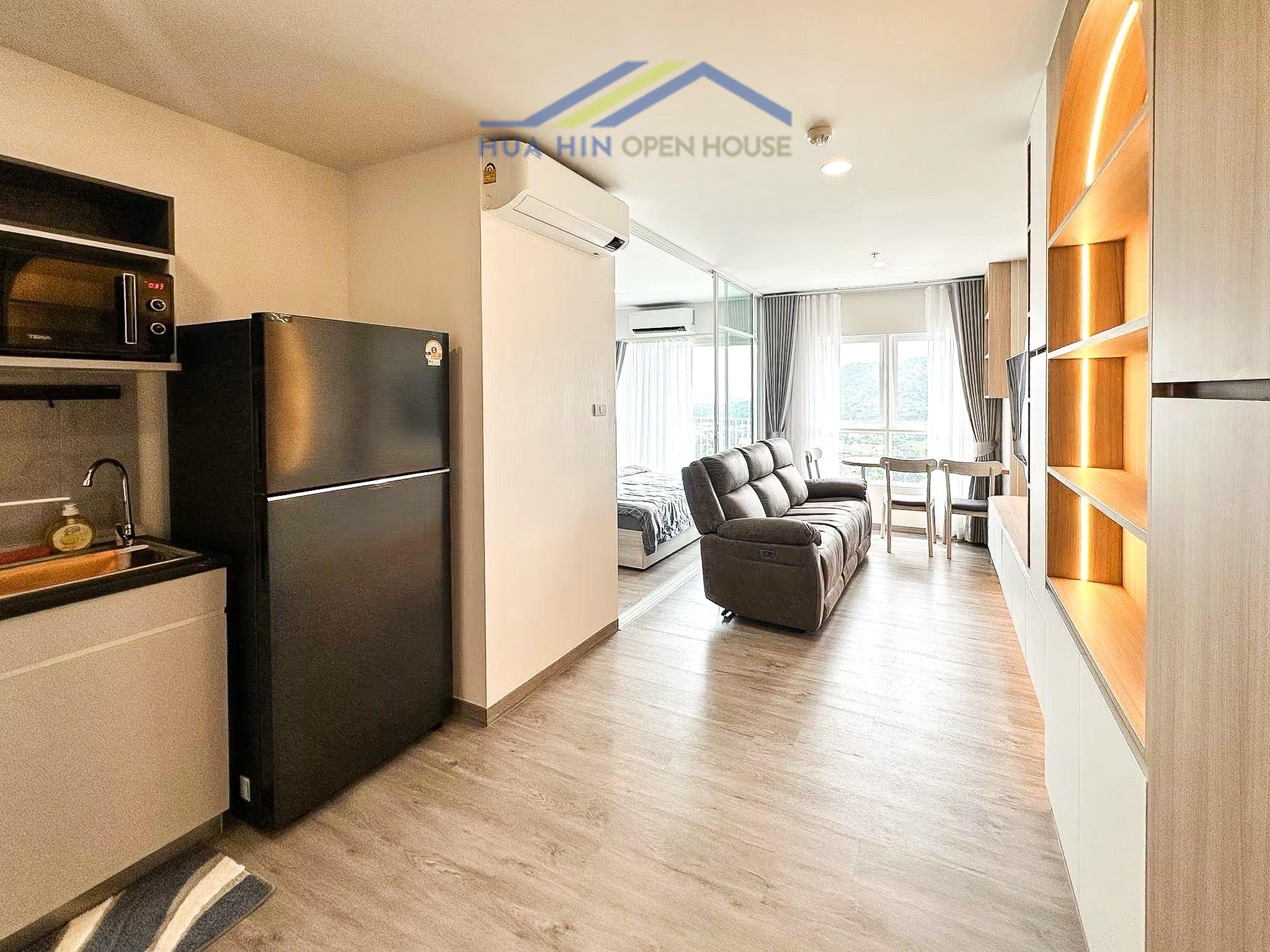Supalai Blue Whale Hua Hin condo interior featuring a kitchen, living area with sofa, and dining table, large windows with a sea view.
