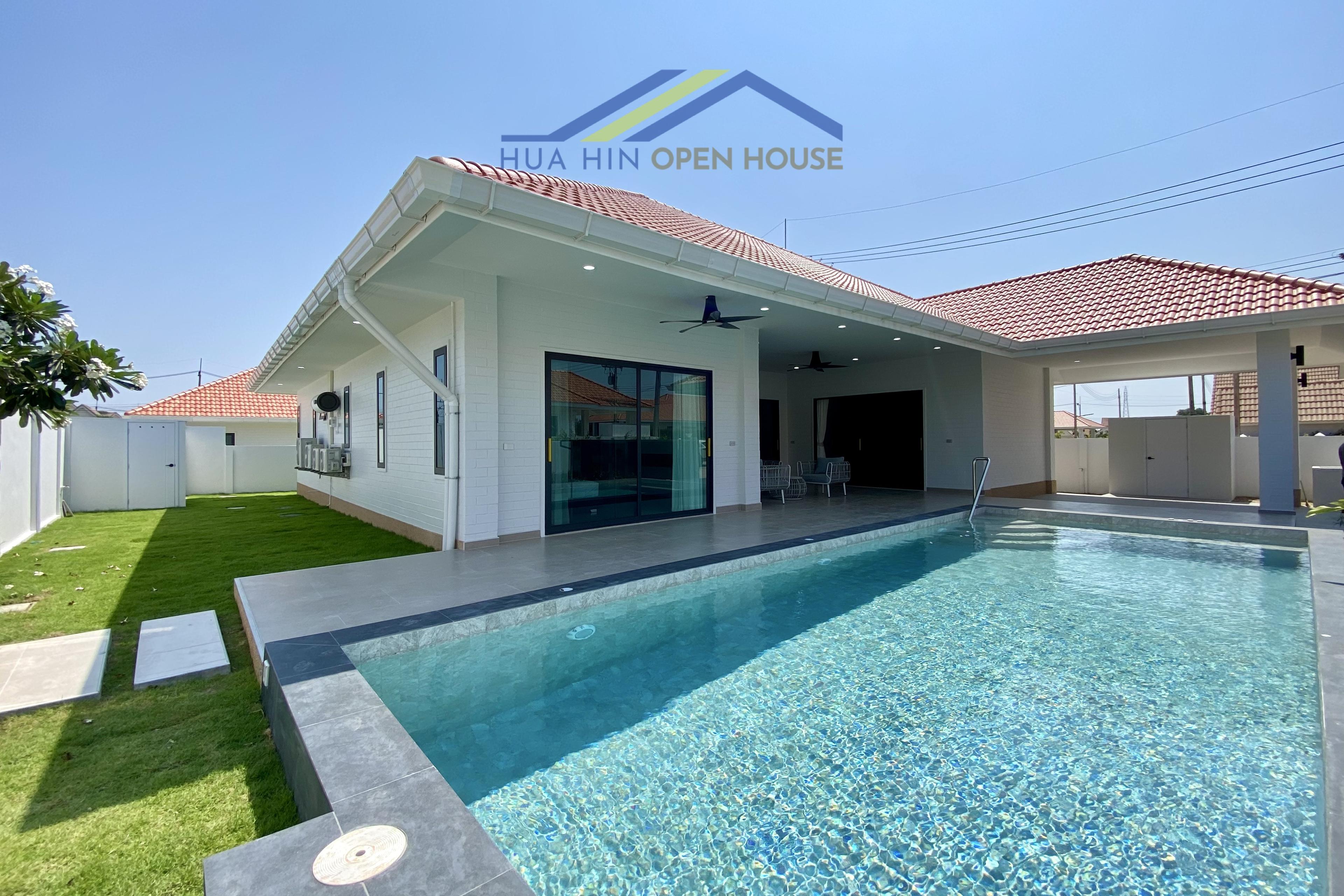 L-shaped pool villa with a sparkling pool, modern design, and lush green lawn in Hua Hin Soi 102.