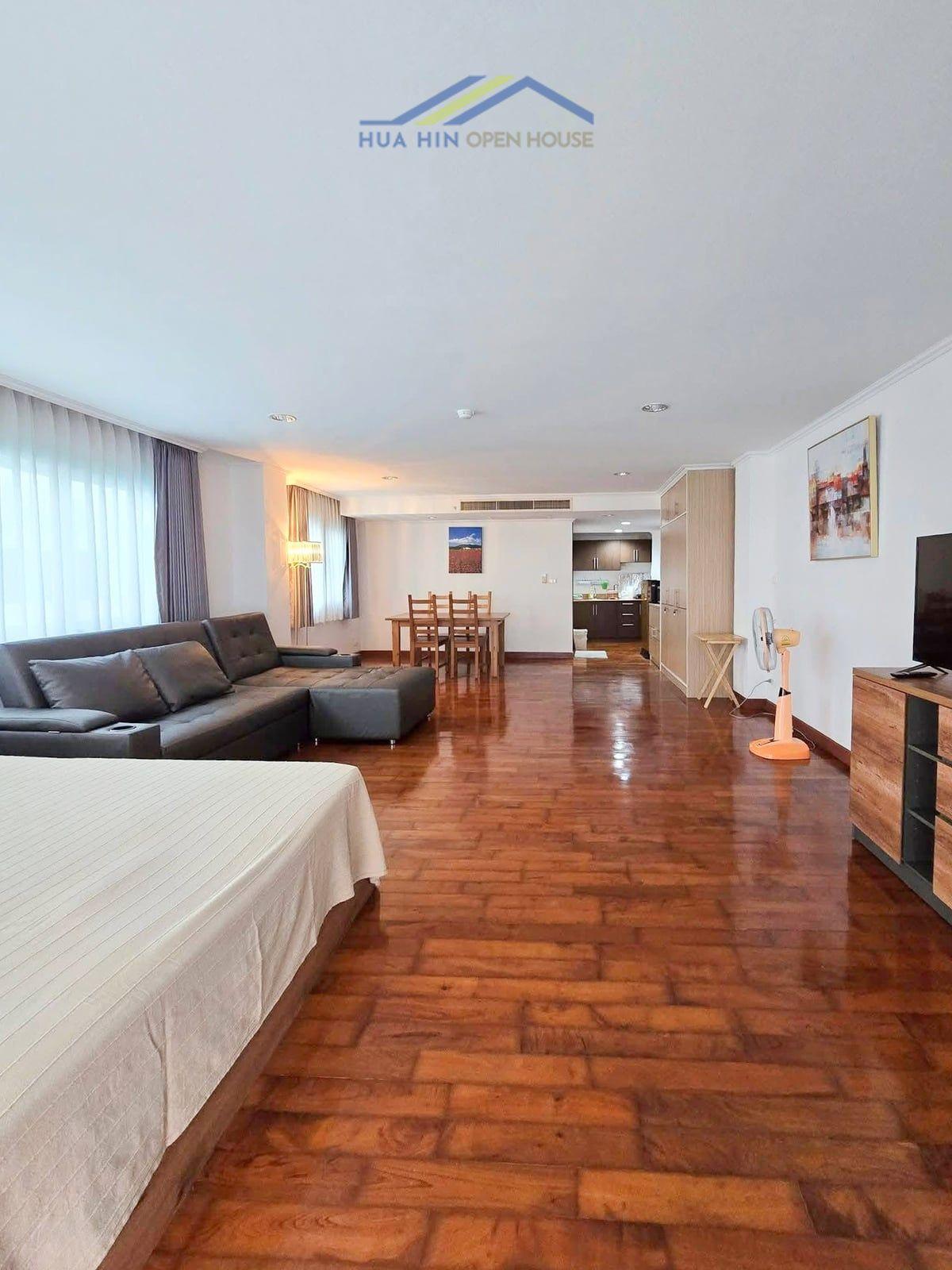 The Beach Palace Cha-Am Spacious living area featuring a sofa, dining table, and kitchen in a beachfront 1-bedroom condo at The Beach Palace.