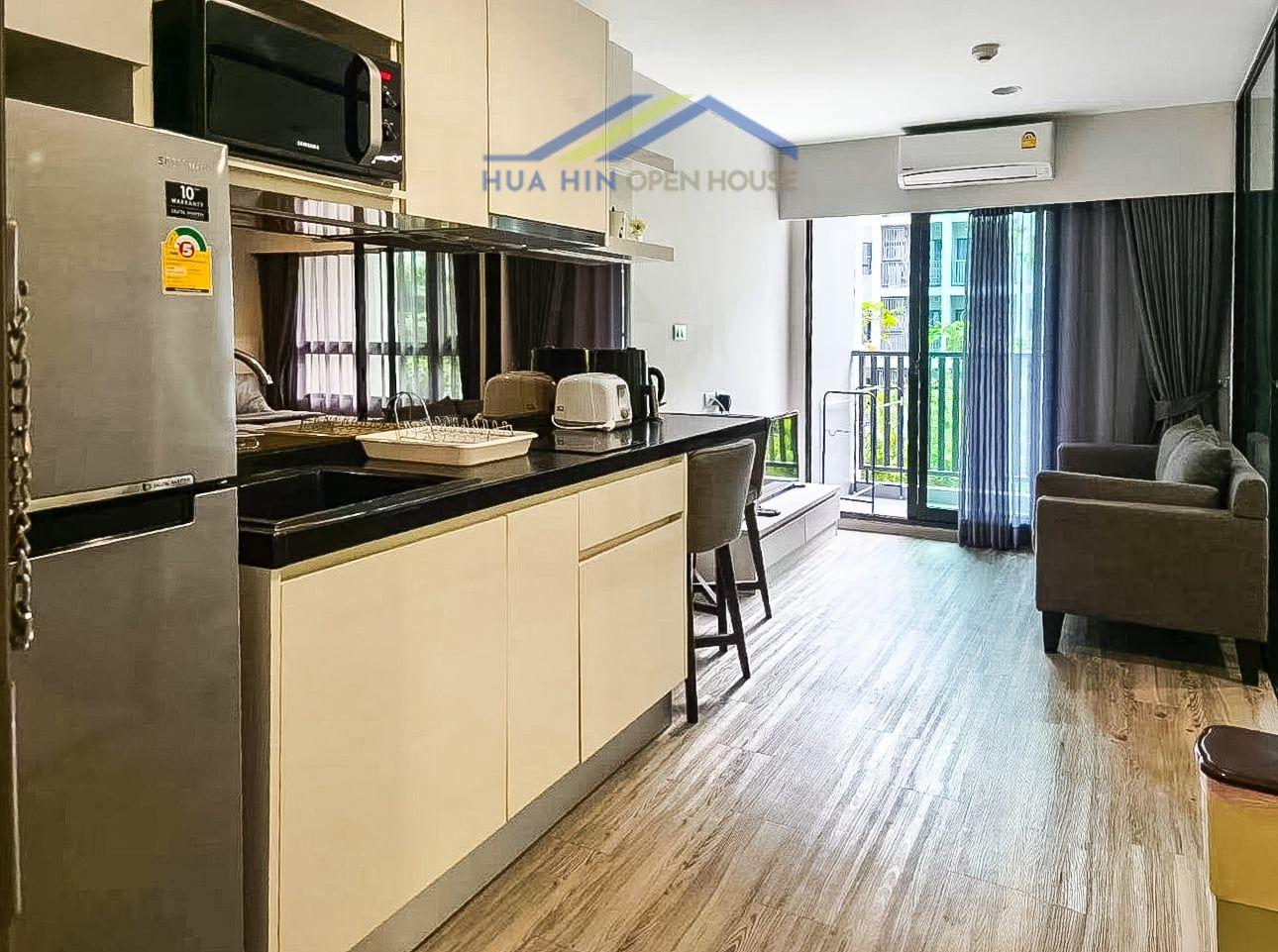 Modern 1-bedroom condo interior featuring a kitchen, living area, and balcony access in central Hua Hin.