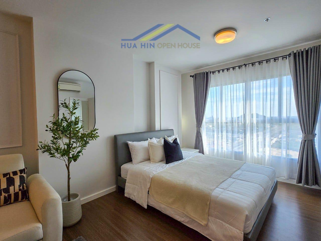 Bright studio condo interior featuring a double bed, modern furnishings, and large windows with scenic views.