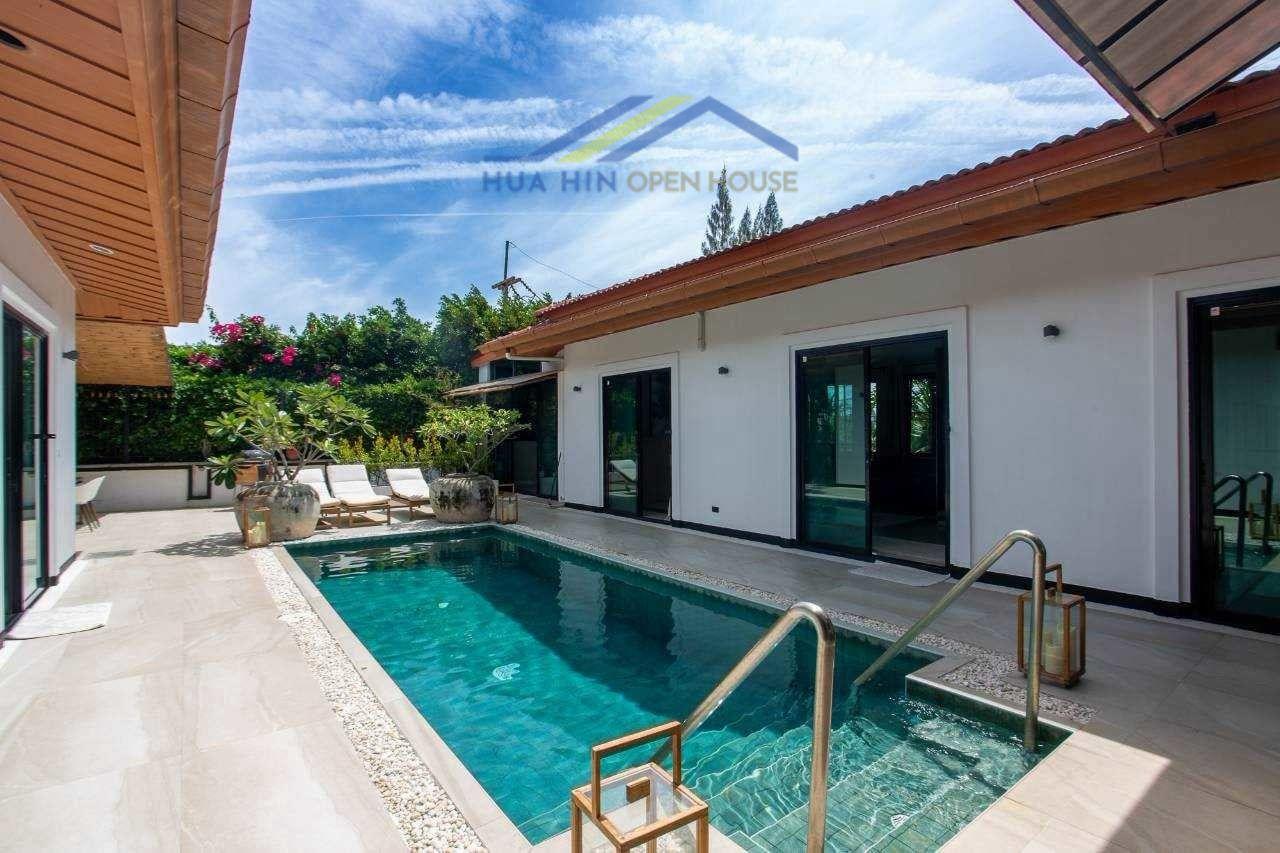 Modern pool villa in Hua Hin with solar power, featuring a private pool, sun loungers, and lush greenery.