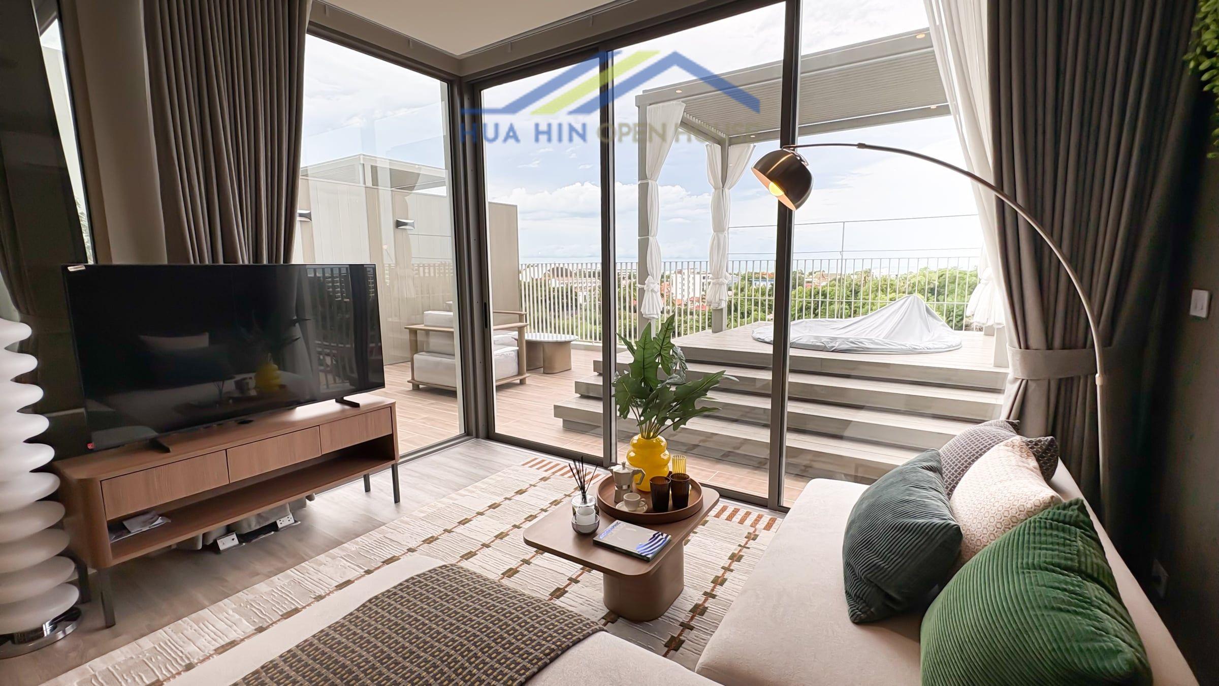 Vehha Hua Hin Modern living area with a TV, stylish decor, and large windows showcasing a private terrace with sea views.
