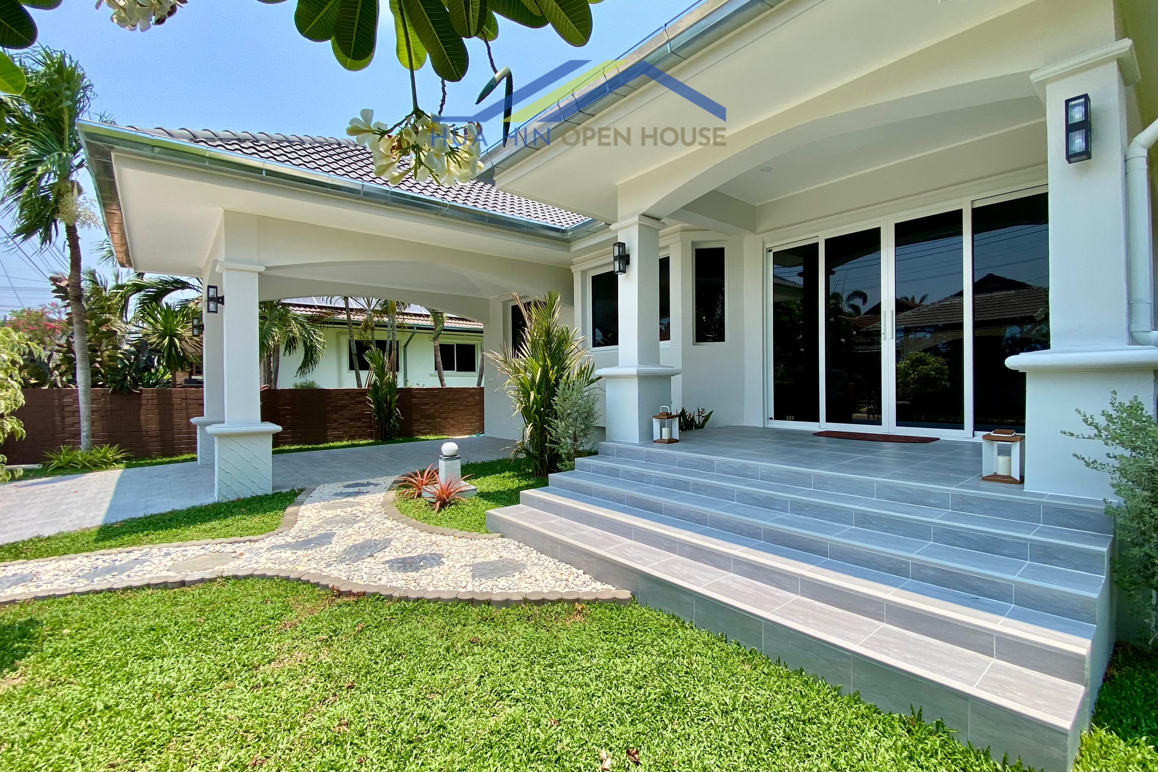 Modern 3-bedroom pool villa entrance with landscaped garden, stone pathway, and spacious steps leading to glass doors.