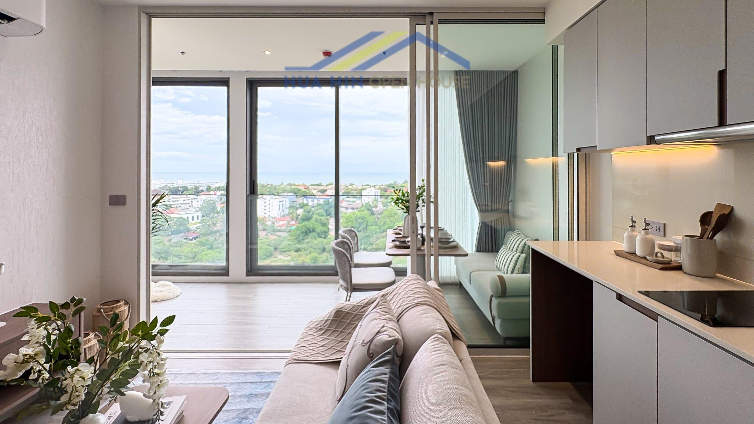 Modern living area with sea views, featuring a cozy sofa, dining table, and stylish kitchen in a luxury condo.