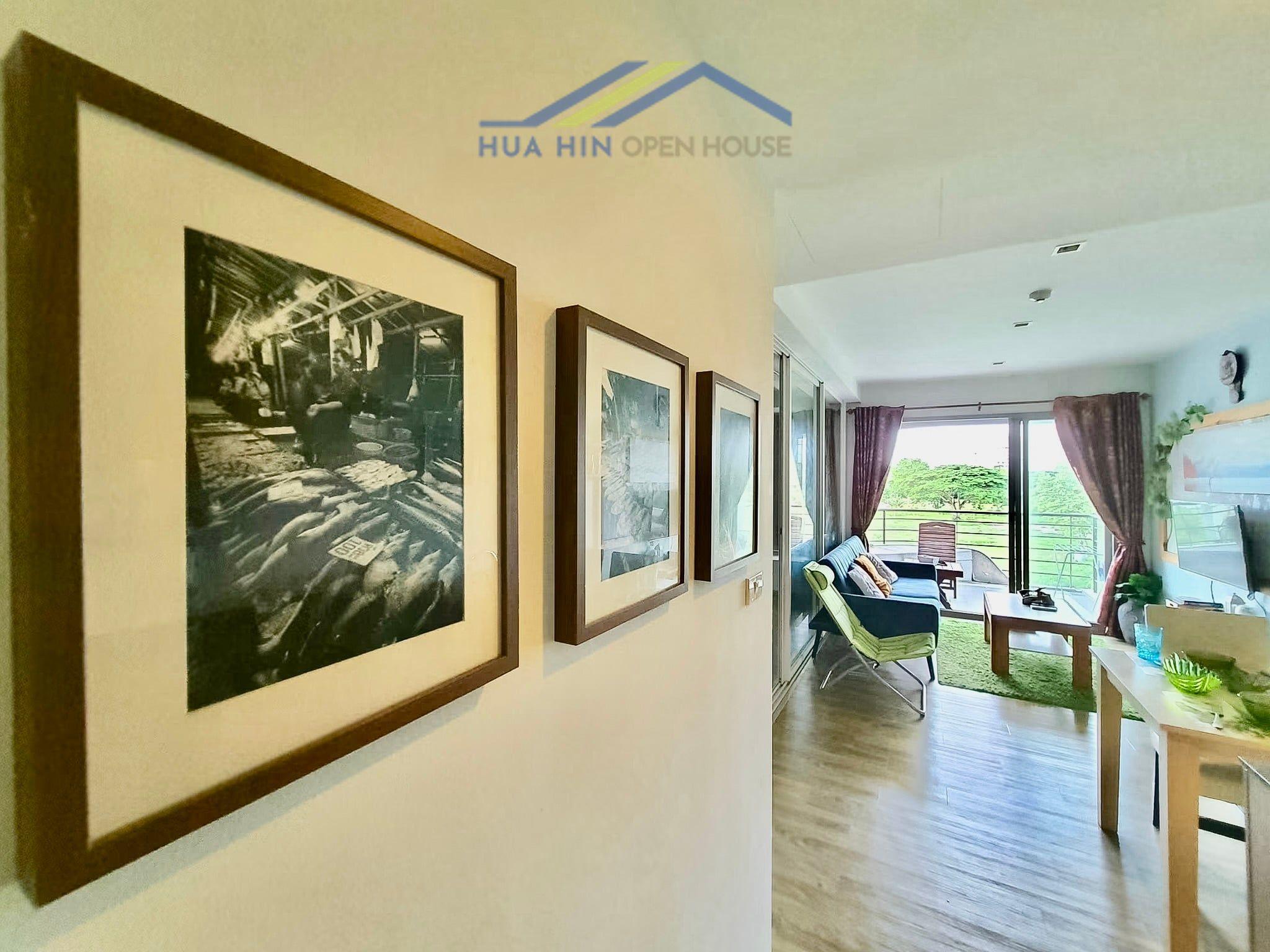 Baan San Ngam Hua Hin condo Artfully framed black-and-white photographs adorn the hallway, leading to a bright, airy living area with views.