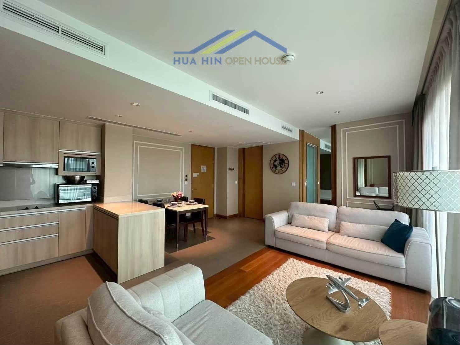Modern living area with a sofa, dining table, and kitchen in a spacious 2-bedroom condo at Amari Hua Hin.
