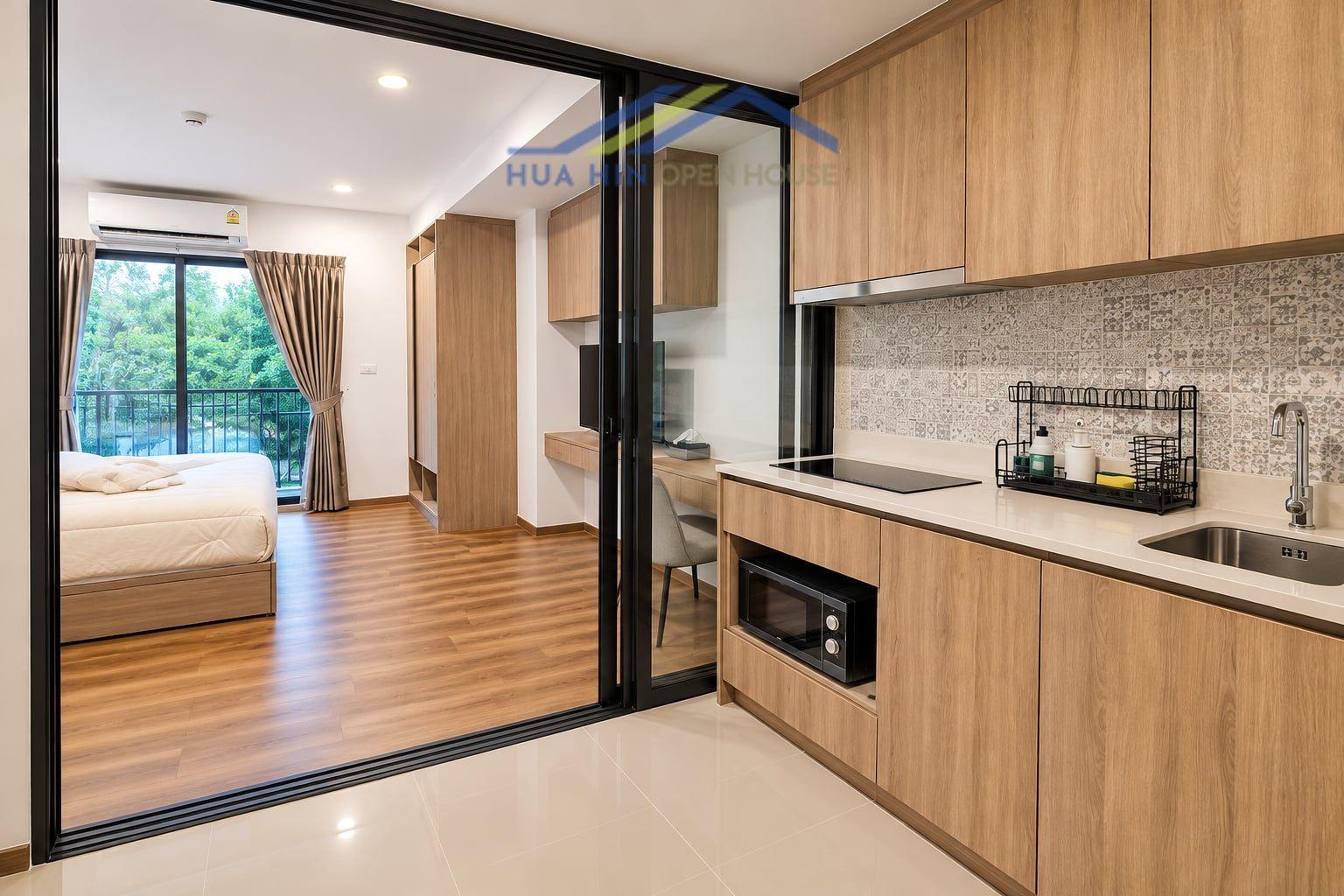 Modern 1-bedroom condo featuring a stylish kitchen, living area, and balcony with green views in La Habana Hua Hin.
