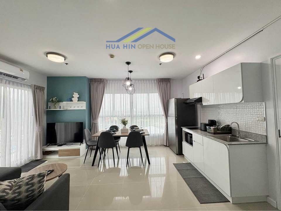 Bright and modern open-concept living area with kitchen, dining space, and large windows in a renovated corner condo.